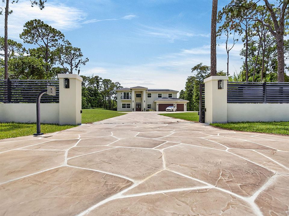 Front elevation of 6077 NW 71st Ter, a 2024 custom estate viewed through an open euro-tile gate